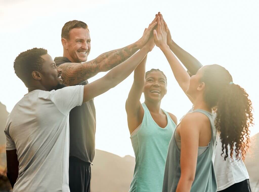 Shot of a group of friends high fiving one another before a workout